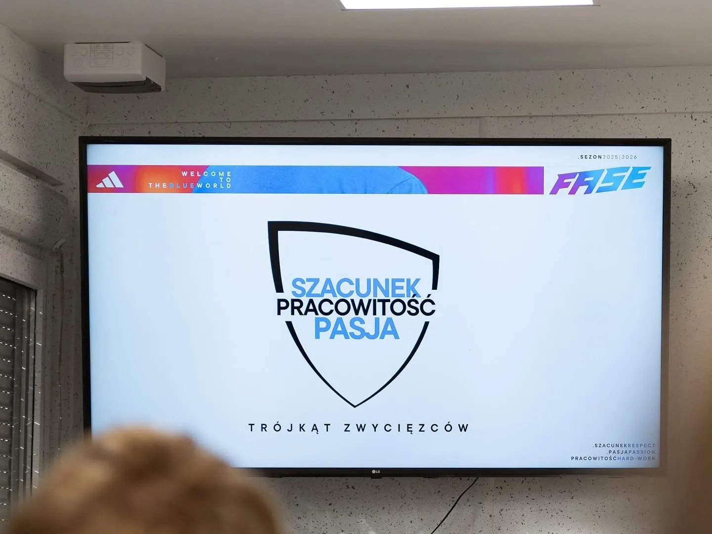 Ekran z klubowym godłem i hasłem: szacunek, pracowitość, pasja — trójkąt zwycięzców